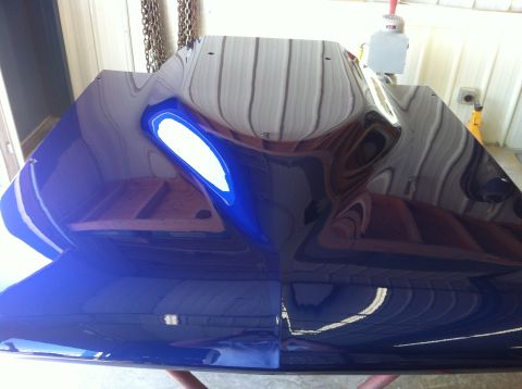 1965 Ford Fairlane - A reflective blue car hood is shown from a top-down perspective, with reflections of overhead lights and structures visible.