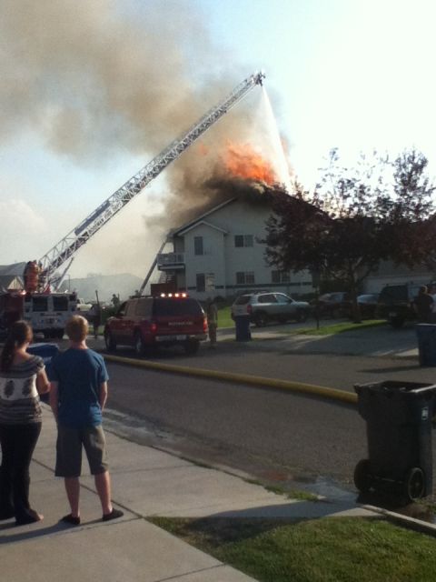 2006 Ford E350 - Emergency responders work to extinguish a house fire, with a ladder truck directing water onto the flames.