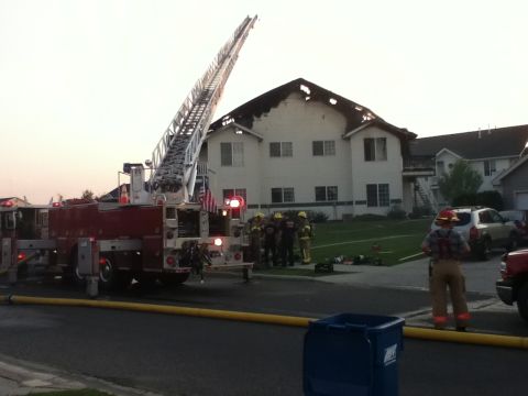 2006 Ford E350 - Emergency responders are on the scene of a fire with a damaged building and a fire truck.