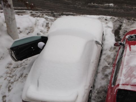 1995 Ford Probe - Two cars are parked side-by-side, both covered in snow, with one car's door ajar.