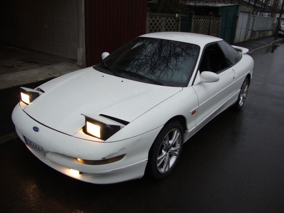 White Ford Probe with pop-up headlights on a wet street