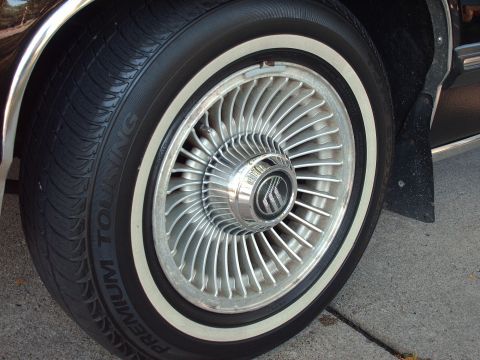 1991 Mercury Grand Marquis - Close-up of a 1991 Mercury Grand Marquis wheel a chrome hubcap with the Mercury logo and a whitewall tire.