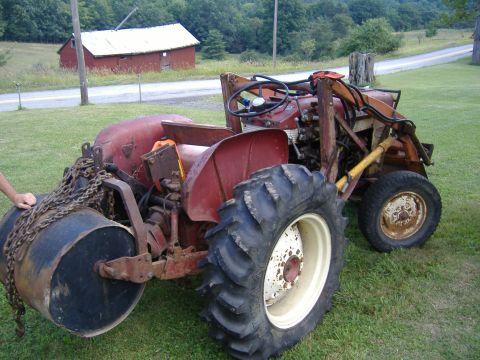 1988 Ford Bronco - Tractor with roller attachment in a rural setting, with a red barn in the background.