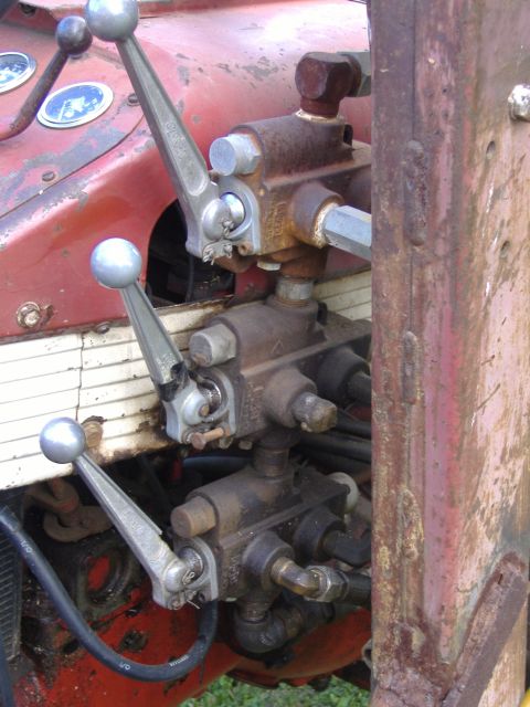 1988 Ford Bronco - Hydraulic control levers and valves on a tractor. The red bodywork shows some wear and tear.