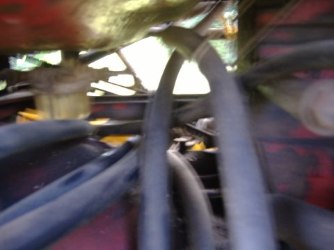 1988 Ford Bronco - Close-up view of engine hoses and red metal components, likely from a tractor or heavy machinery.