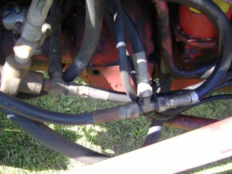 1988 Ford Bronco - Close-up of hydraulic hoses and fittings on a red machine, with a "SUPERMOTORS" logo in the corner.