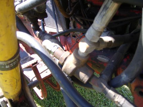 1988 Ford Bronco - Detail shot of hydraulic lines and engine components, with visible text on a yellow cylinder and a SuperMotors watermark.