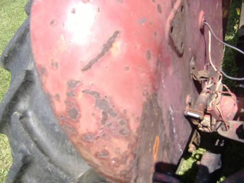 1988 Ford Bronco - Detail of a rusty red tractor fender and tire, showing wear and tear.