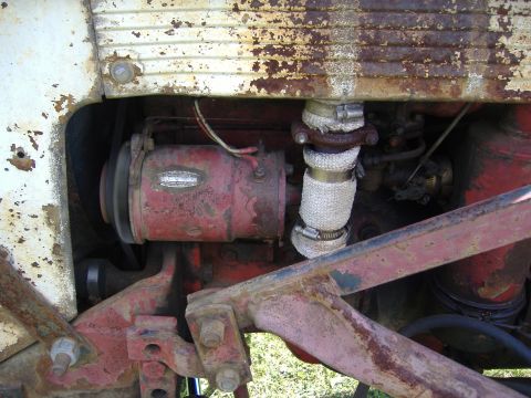 1988 Ford Bronco - Detail of a tractor's engine, showing the generator and exhaust system with visible rust.