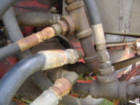 1988 Ford Bronco - This image shows a close-up view of various hydraulic hoses and metal fittings, some of which appear to be rusted.