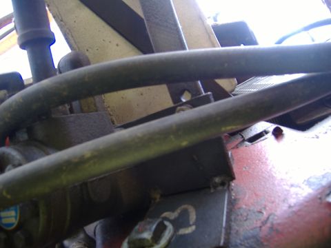 1988 Ford Bronco - Close-up view of engine parts, including metal tubes and a small emblem.
