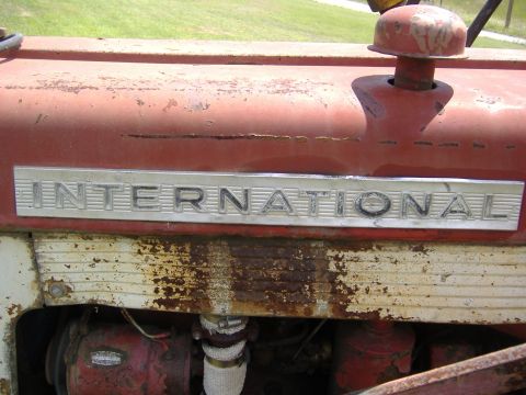 1988 Ford Bronco - Close-up of the 'INTERNATIONAL' badge on a weathered tractor.