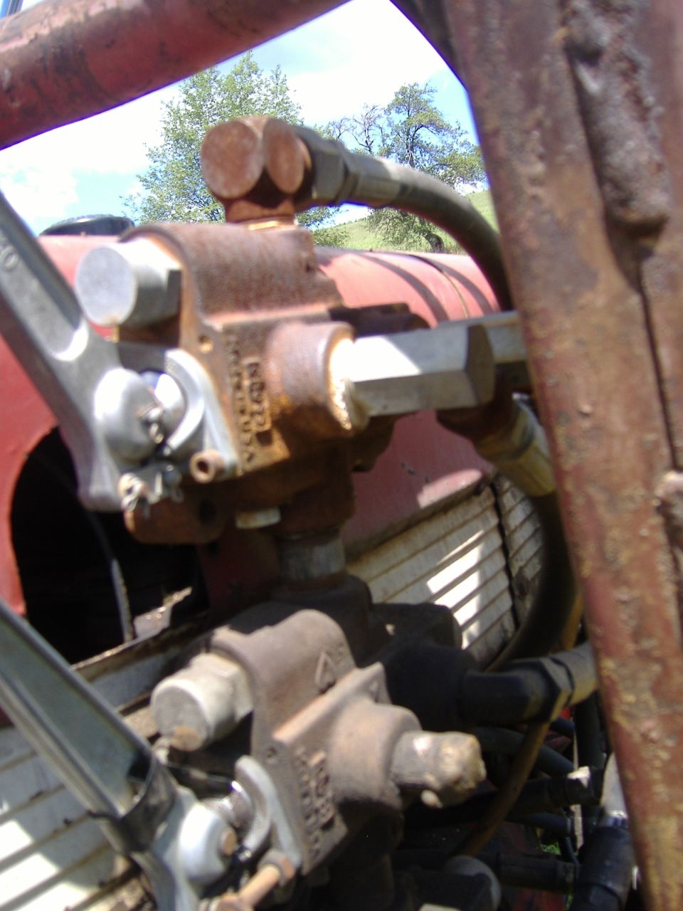 Close-up of hydraulic pump and hoses on a red tractor