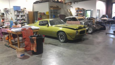 1973 Chevrolet Camaro - A yellow 1973 Chevrolet Camaro is parked in a garage with other vehicles and equipment.