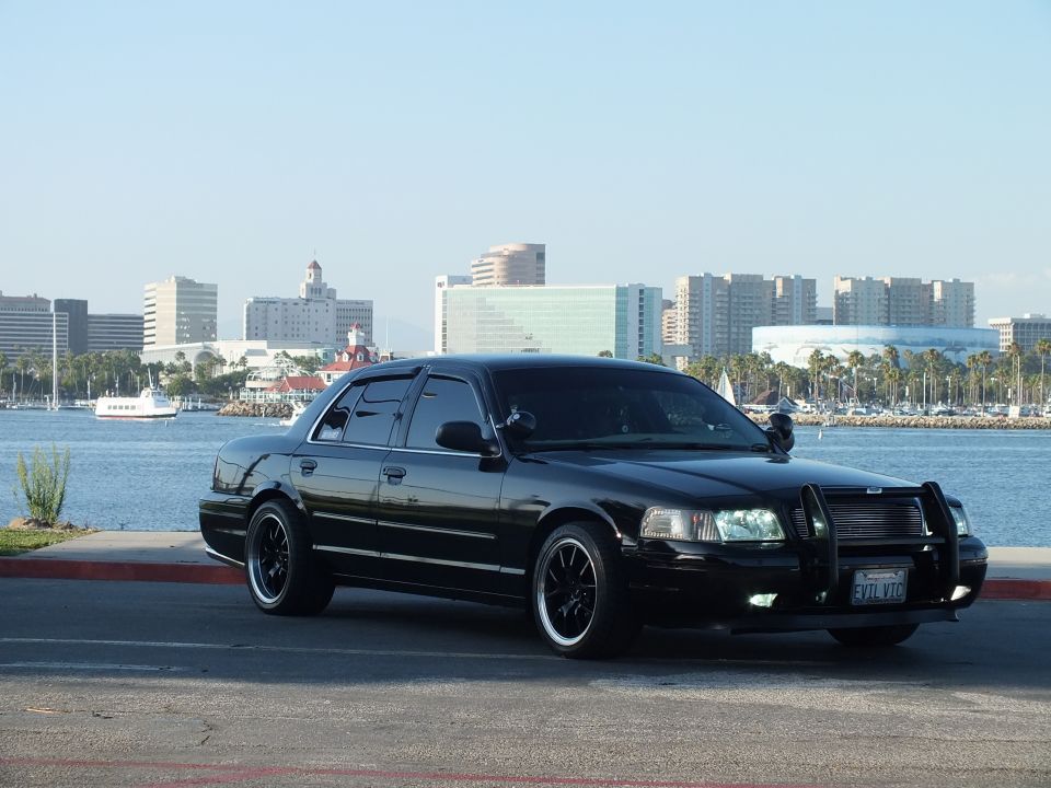 Black Ford Crown Victoria sedan with push bar parked at Long Beach waterfront, EVIL VIC plate