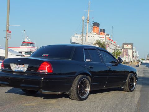 2003 Ford Crown Victoria - Murdered-out Ford sedan from the rear with the Queen Mary and boats docked in the background