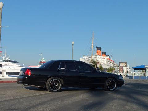 2003 Ford Crown Victoria - Lowered blacked-out sedan shot in profile against the Queen Mary and docked ferries