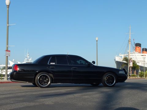 2003 Ford Crown Victoria - Lowered blacked-out sedan in profile by the harbor with the Queen Mary and boats beyond