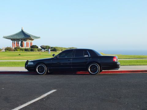 2003 Ford Crown Victoria - Lowered black sedan parked along a curb, sweeping ocean view and pagoda pavilion in the background.