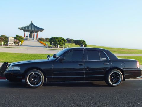 2003 Ford Crown Victoria - Side view of a lowered black four-door on a curb, pagoda pavilion and water filling the background.