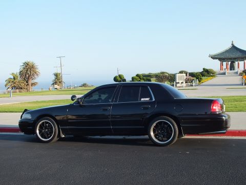 2003 Ford Crown Victoria - Profile of a lowered black four-door, palms and a pagoda framing the coastal park behind it.