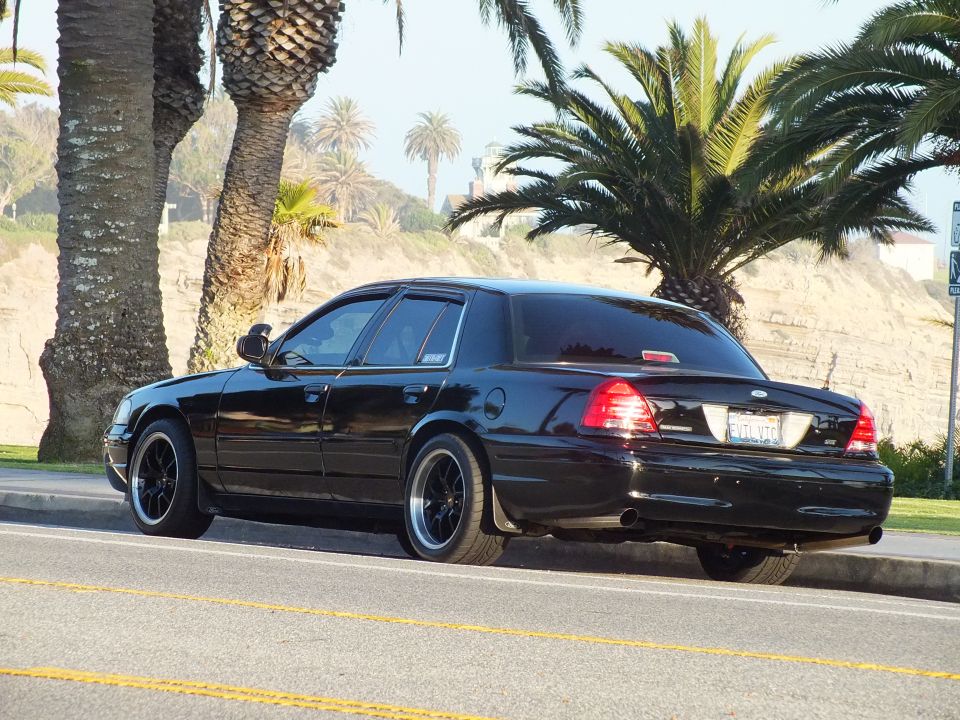 Black sedan rear view with California plate parked at oceanfront curb