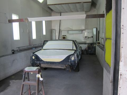 1991 Ford LTD Crown Victoria - A car is being prepped for painting inside a professional paint booth, with its front end covered.