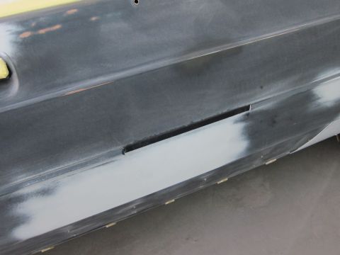 1991 Ford LTD Crown Victoria - Close-up of a car door panel undergoing bodywork, with primer and masking tape visible.