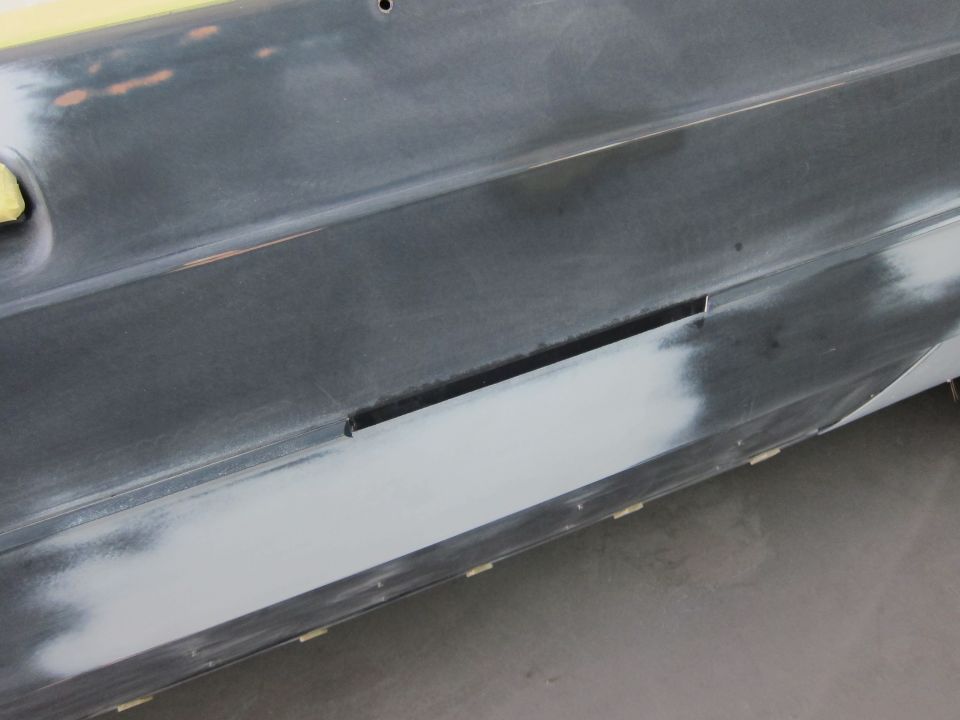 Car door panel with primer and tape, showing a long horizontal slot
