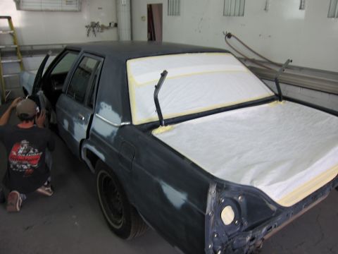 1991 Ford LTD Crown Victoria - A dark sedan is undergoing bodywork in a garage, with the trunk and rear window covered.