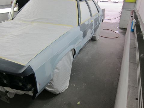 1991 Ford LTD Crown Victoria - A sedan, likely a Ford Crown Victoria, is covered in protective sheeting and tape as it is prepared for a paint job.