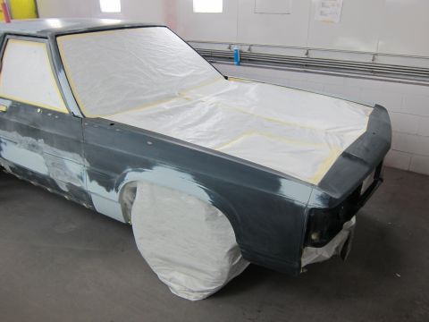 1991 Ford LTD Crown Victoria - A car is being prepped for painting in a workshop, with windows and body panels covered.