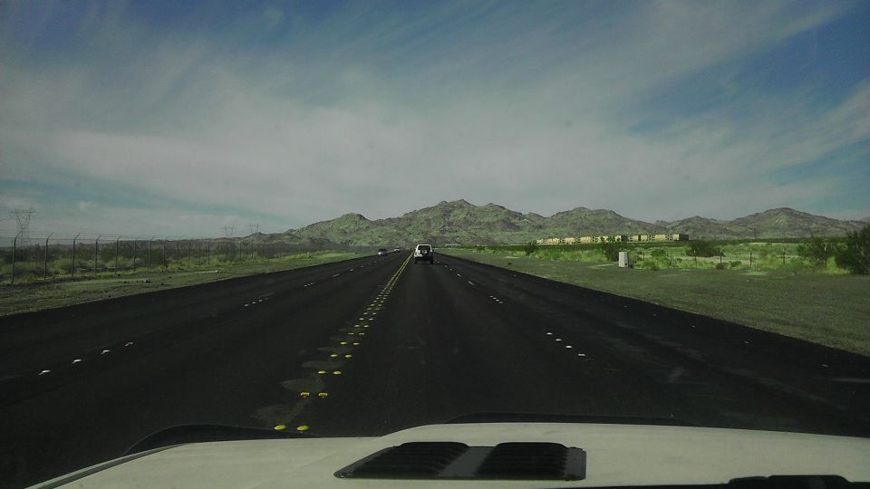 White SUV on a highway in a desert landscape with mountains in the background