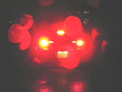 1997 Ford Taurus - Night shot of a car's lit front end in near-total darkness, with red neon or underglow washing the body and headlights, fog lamps and an il…