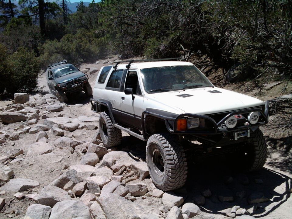 White Toyota 4Runner with off-road modifications on a rocky trail, front-right view