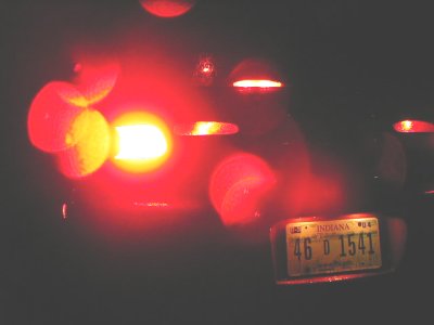 1997 Ford Taurus - The rear of a vehicle is shown at night, with bright red taillights illuminated.
