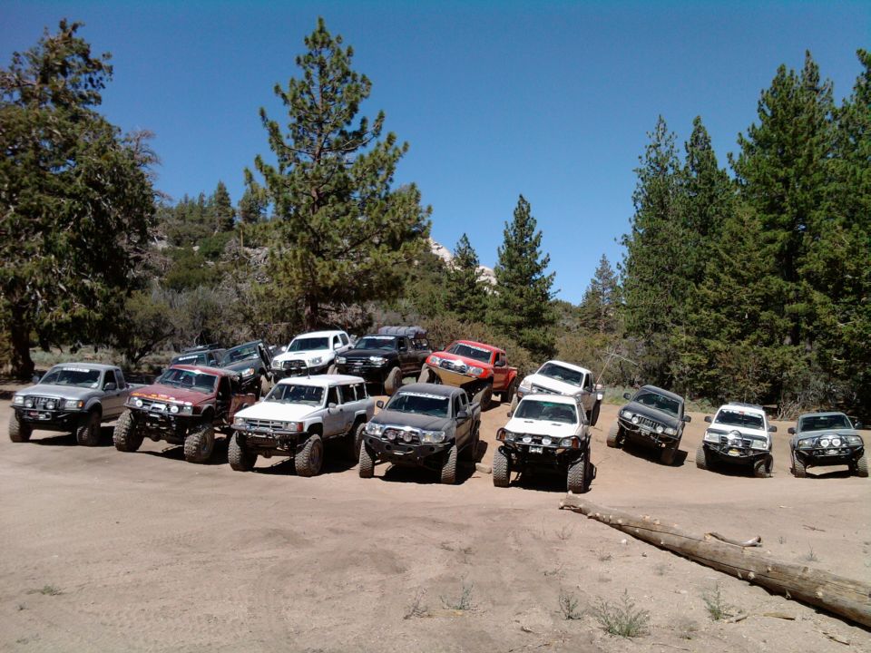 Group of modified Toyota 4x4s parked on dirt, some with lifted suspensions and off-road tires