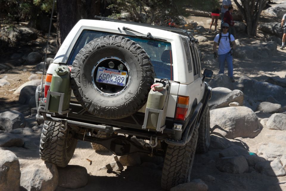 1985 Toyota 4Runner with spare tire and jerry cans on rear bumper, navigating rocky terrain