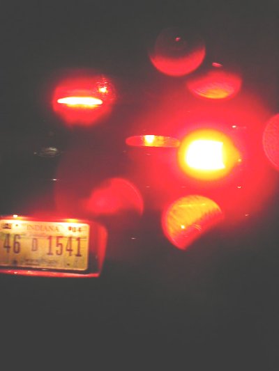 1997 Ford Taurus - The rear of a 1997 Ford Taurus is visible, with its brake lights illuminated and an Indiana license plate.