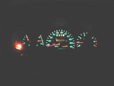 1997 Ford Taurus - Instrument cluster photographed in the dark, showing green backlit gauges with a central MPH speedometer reading to 110, a mechanical odome…