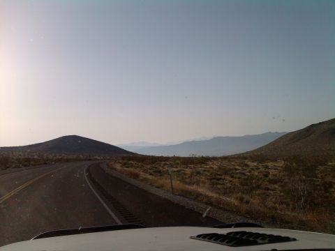 1985 Toyota 4Runner - View from inside a vehicle driving on a road through a desert landscape with distant mountains.