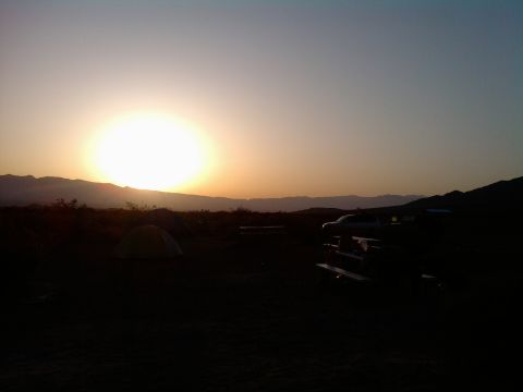 1985 Toyota 4Runner - A truck is parked at a campsite with a tent set up, silhouetted against a desert sunset.