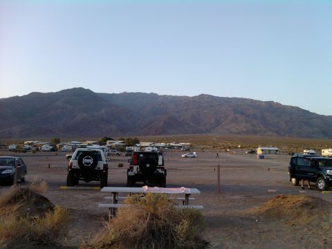 1985 Toyota 4Runner - Several vehicles are parked in a lot with mountains under a clear sky.