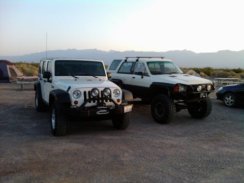 1985 Toyota 4Runner - Two off-road vehicles, a white Jeep and a white Toyota 4Runner, are parked in a desert landscape.