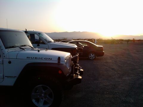 1985 Toyota 4Runner - Several vehicles parked in a desert landscape during a sunset, with mountains in the background.
