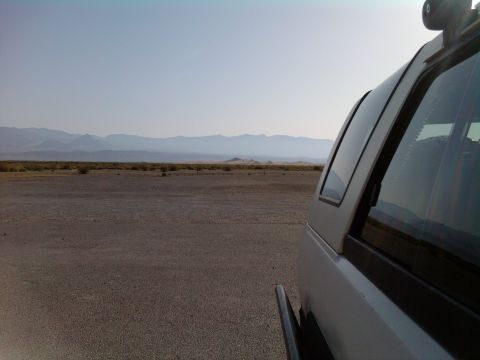 1985 Toyota 4Runner - A silver SUV with a cap is parked in a vast, dry landscape under a clear sky.