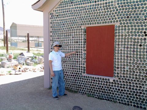 1985 Toyota 4Runner - A person stands next to a building constructed with a wall of green bottles and a red door.