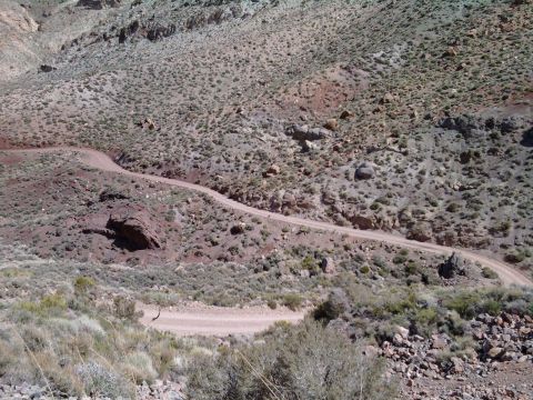 1985 Toyota 4Runner - A dirt road winds through a dry, hilly desert landscape under a clear sky.