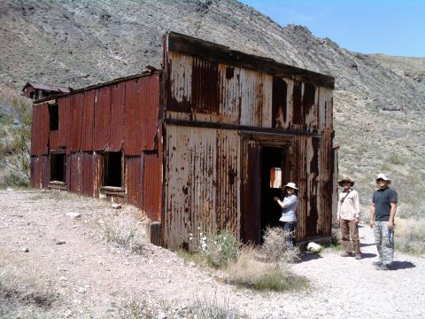 1985 Toyota 4Runner - Three people stand in front of a derelict corrugated metal building in a dry, mountainous area.