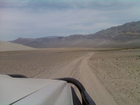 1985 Toyota 4Runner - Driving on a dirt road in a desert landscape with mountains under a cloudy sky.